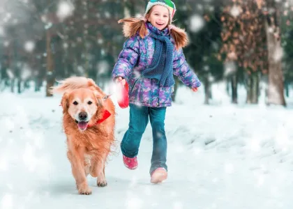 une fille court dans la neige avec un chien